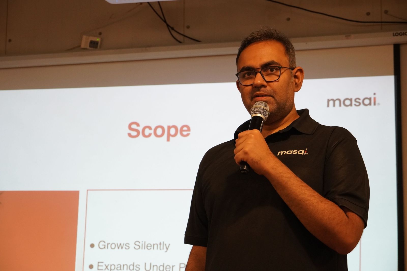 A Masai faculty member speaking with a microphone during a session