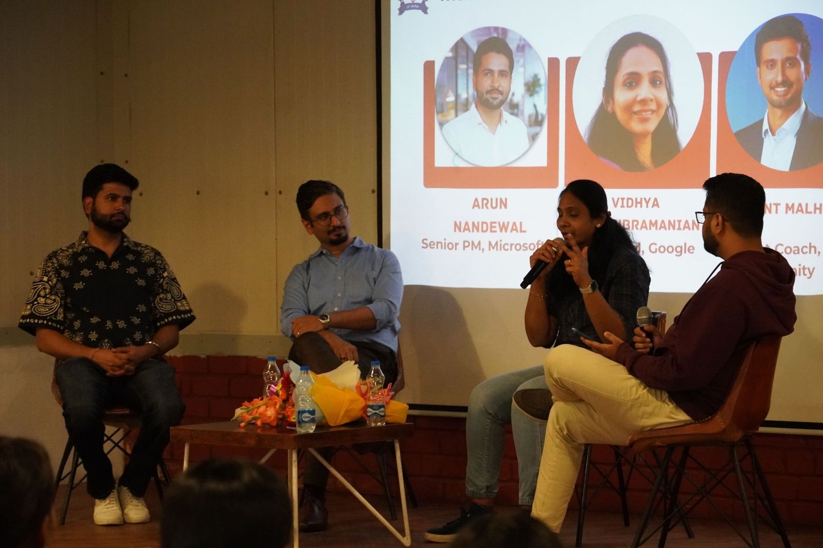 Four speakers on a panel with a presentation behind them